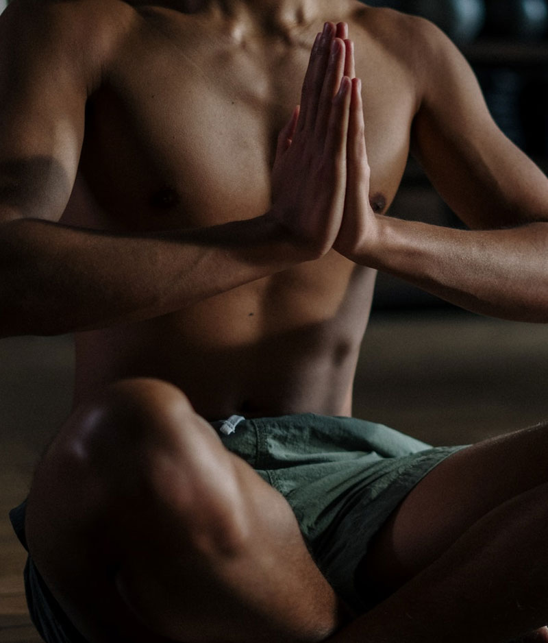 Man sitting cross legged with his hands touching in front of his chest practising Breath Work